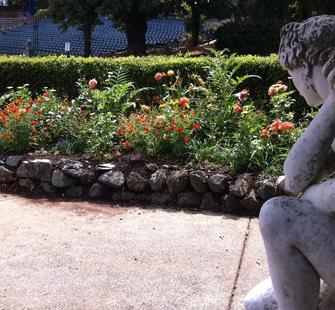 A sculpture admires a nearby flower bed
